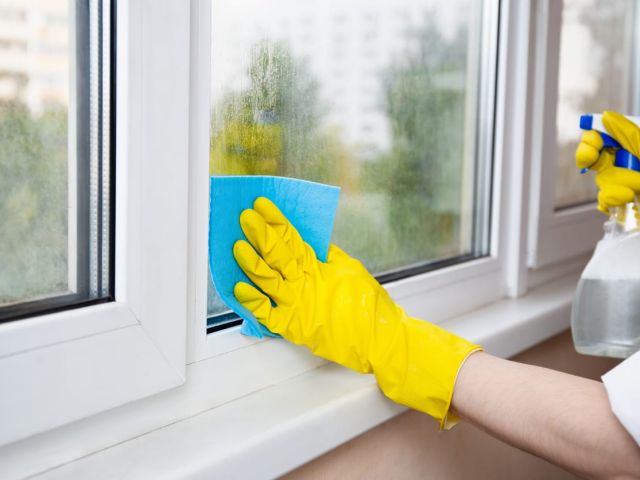 Cleaning A Window With A Spray Bottle And Sponge Cloth